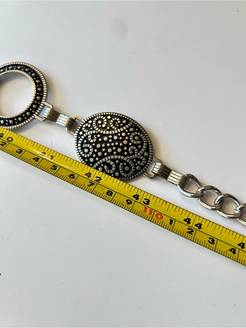 Silver-tone chain belt features textured medallion links and a hook closure L/XL